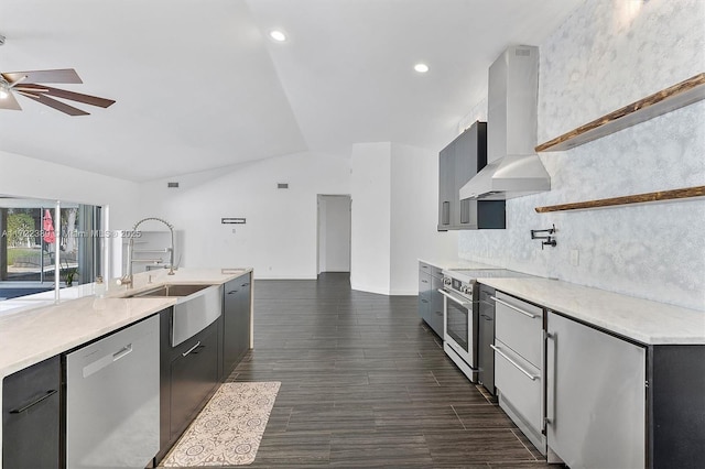 kitchen featuring ceiling fan, sink, wall chimney exhaust hood, lofted ceiling, and appliances with stainless steel finishes