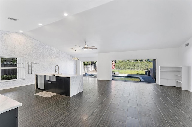 unfurnished living room featuring sink, ceiling fan with notable chandelier, and vaulted ceiling