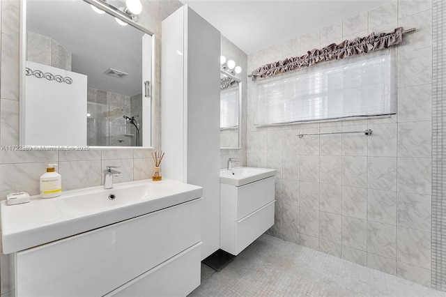 bathroom with a shower with door, vanity, tile walls, and tile patterned flooring