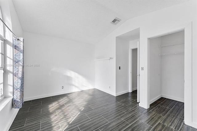 unfurnished bedroom with a textured ceiling, a closet, and vaulted ceiling