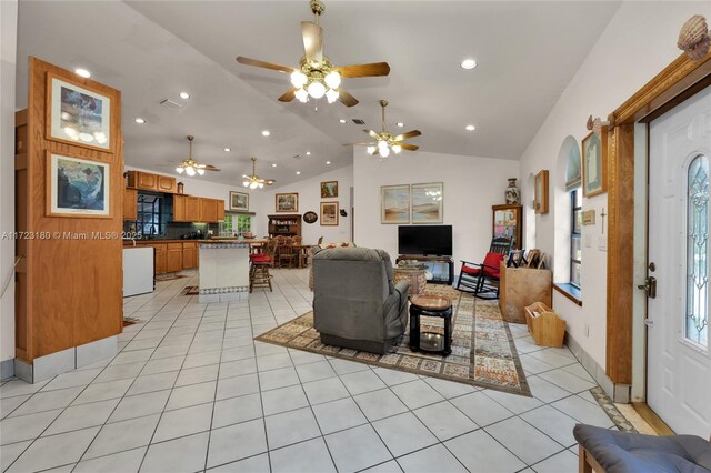 tiled living room with vaulted ceiling, ceiling fan, and a healthy amount of sunlight