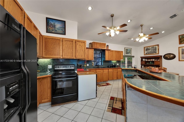 kitchen with tile counters, lofted ceiling, decorative backsplash, light tile patterned floors, and black appliances