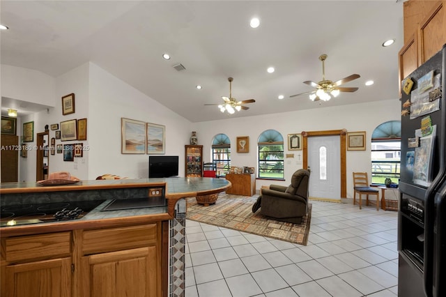 living room with ceiling fan, light tile patterned floors, and lofted ceiling