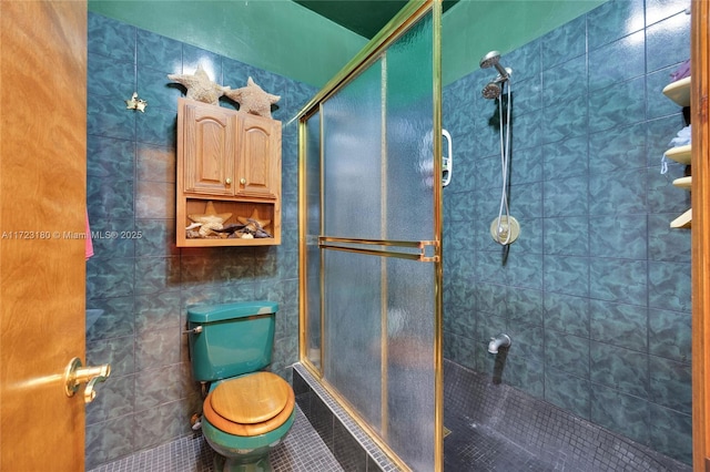 bathroom with tile patterned floors, a shower with shower door, and toilet