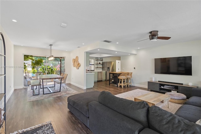 living room featuring ceiling fan and dark wood-type flooring