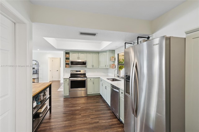 kitchen featuring dark wood-type flooring, exhaust hood, a raised ceiling, sink, and appliances with stainless steel finishes