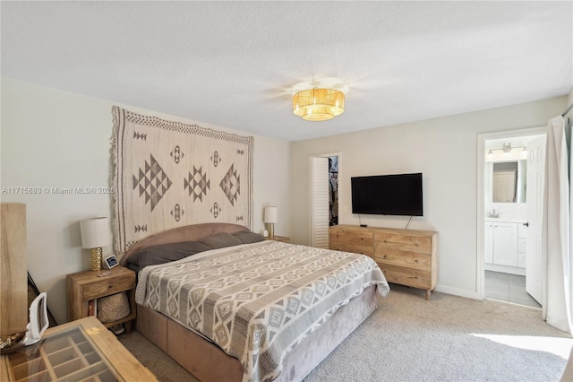 carpeted bedroom with a textured ceiling, a spacious closet, ensuite bath, and a closet