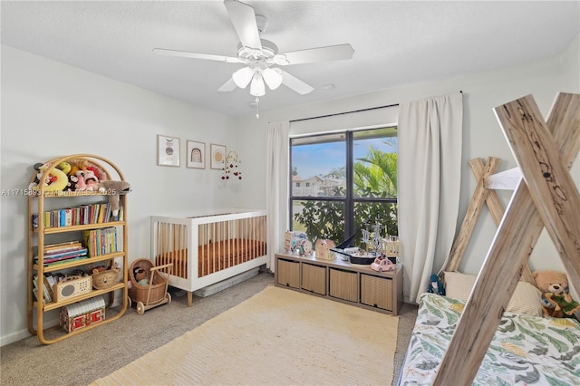 bedroom with carpet flooring, ceiling fan, a textured ceiling, and a nursery area