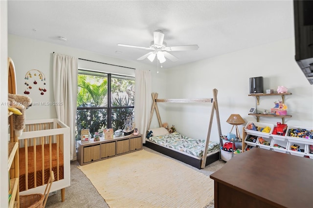 bedroom featuring carpet flooring, a nursery area, and ceiling fan