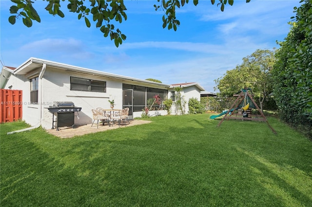 back of property with a sunroom, a playground, a yard, and a patio