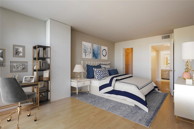 bedroom with a walk in closet, hardwood / wood-style floors, and connected bathroom