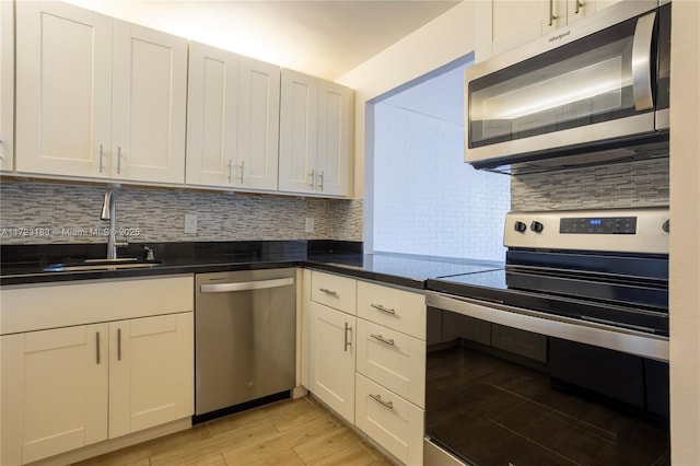 kitchen with white cabinets, sink, stainless steel appliances, and tasteful backsplash