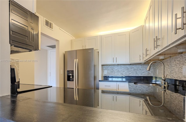 kitchen featuring white cabinets, backsplash, sink, and stainless steel refrigerator with ice dispenser