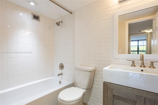 full bathroom featuring tiled shower / bath combo, toilet, and vanity