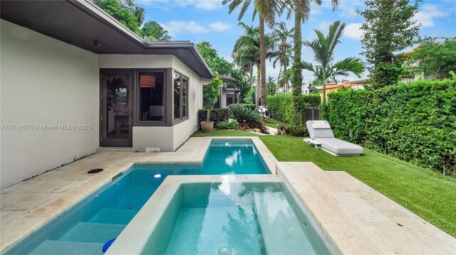 view of pool featuring a hot tub and a lawn