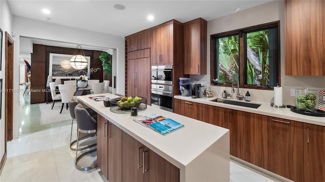 kitchen with sink, light tile patterned flooring, a kitchen bar, a center island, and stainless steel oven