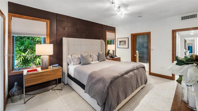 bedroom featuring rail lighting, multiple windows, and ensuite bath