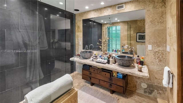 bathroom featuring vanity, a shower, and tile walls