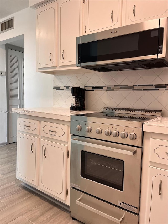 kitchen featuring light wood-type flooring, stainless steel appliances, and tasteful backsplash