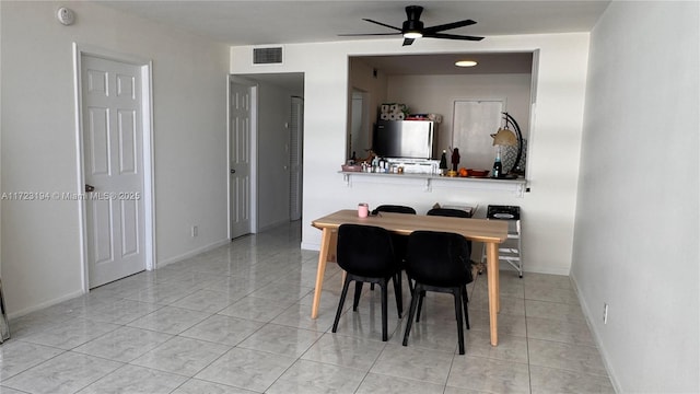 tiled dining room featuring a ceiling fan, visible vents, and baseboards