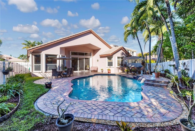 view of pool with pool water feature, a sunroom, and a patio area