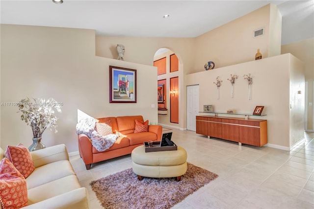 living room featuring light tile patterned flooring and a towering ceiling