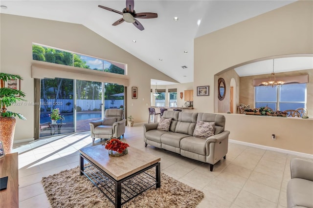 living room featuring light tile patterned floors, ceiling fan with notable chandelier, and plenty of natural light