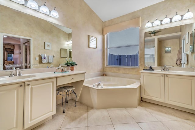 bathroom with tile patterned floors, vanity, a bath, and vaulted ceiling