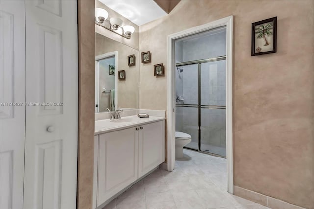 bathroom featuring tile patterned floors, vanity, toilet, and a shower with shower door