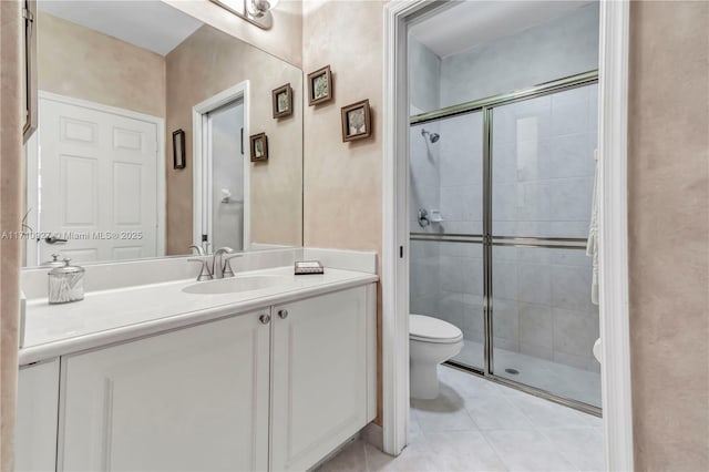 bathroom with tile patterned flooring, a shower with door, vanity, and toilet