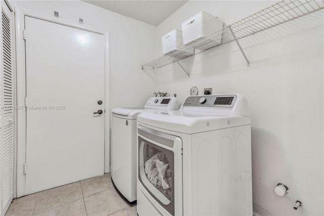 clothes washing area with independent washer and dryer and light tile patterned floors