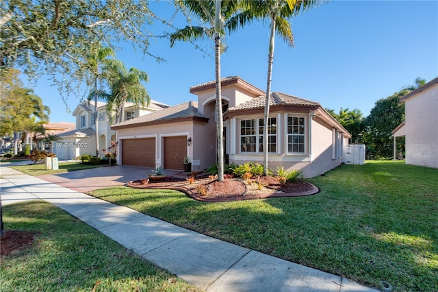 mediterranean / spanish home featuring a garage and a front lawn