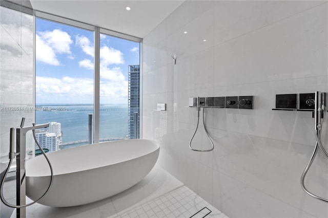 bathroom featuring a water view, expansive windows, tile patterned flooring, and a tub