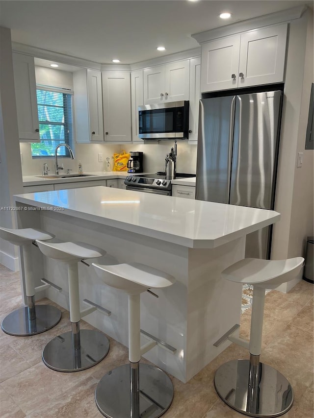 kitchen featuring appliances with stainless steel finishes, a breakfast bar, a sink, and light countertops