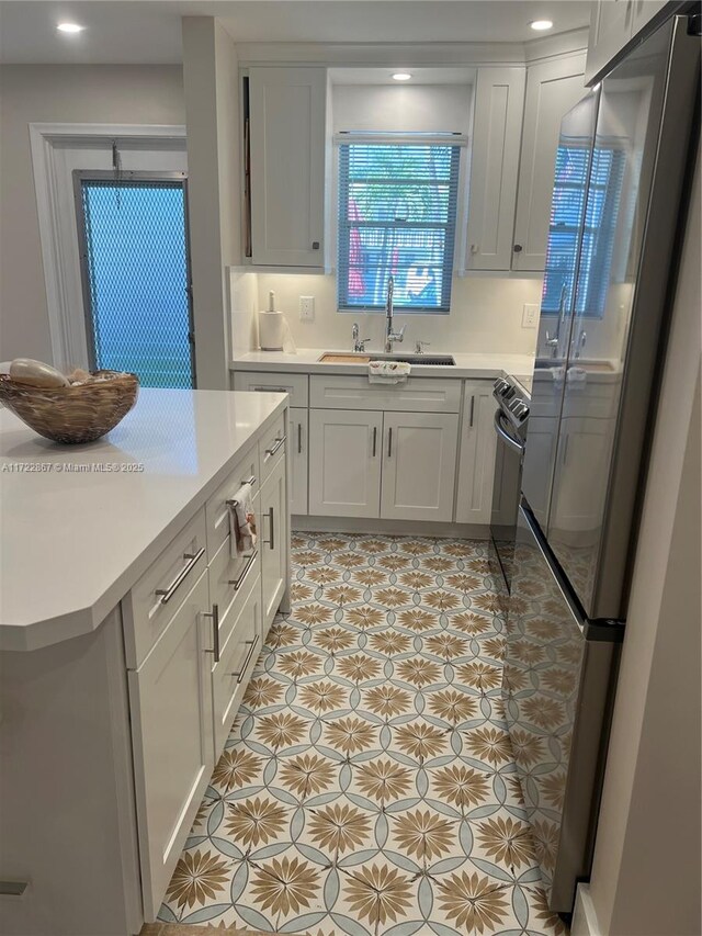 kitchen with a kitchen breakfast bar, sink, white cabinets, and appliances with stainless steel finishes