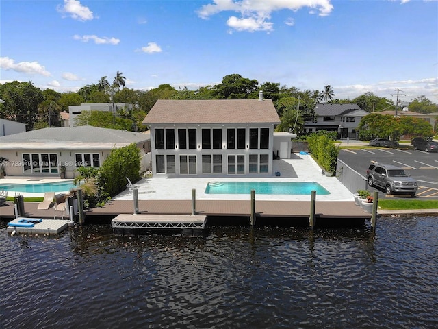 back of house with a patio, a water view, a sunroom, and an outdoor pool