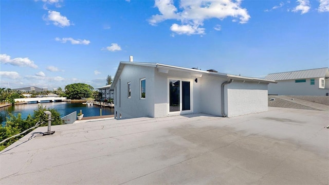 back of property featuring a patio and a water view