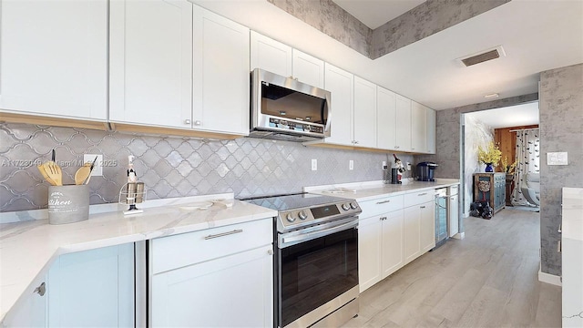 kitchen featuring light stone countertops, appliances with stainless steel finishes, light hardwood / wood-style flooring, and white cabinetry