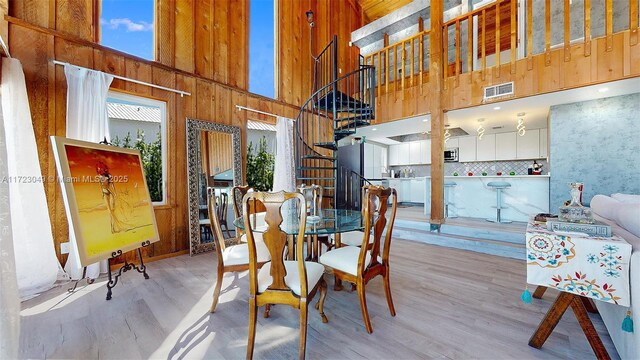 dining area featuring a high ceiling, wooden walls, and hardwood / wood-style floors