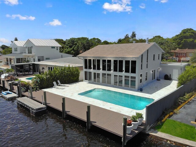 rear view of property featuring a fenced in pool, a water view, and a patio