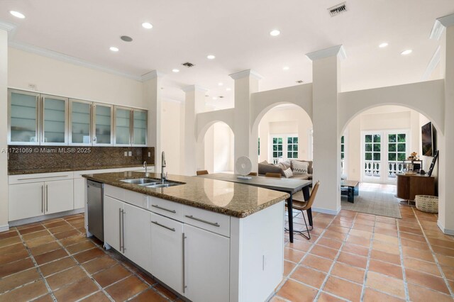 kitchen with decorative backsplash, sink, a center island with sink, and white cabinets