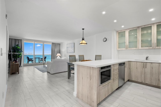 kitchen featuring appliances with stainless steel finishes, floor to ceiling windows, sink, light brown cabinets, and a water view