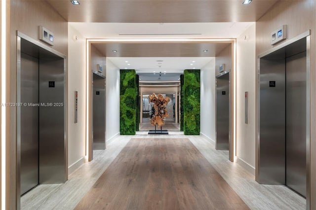 corridor featuring light wood-type flooring and elevator