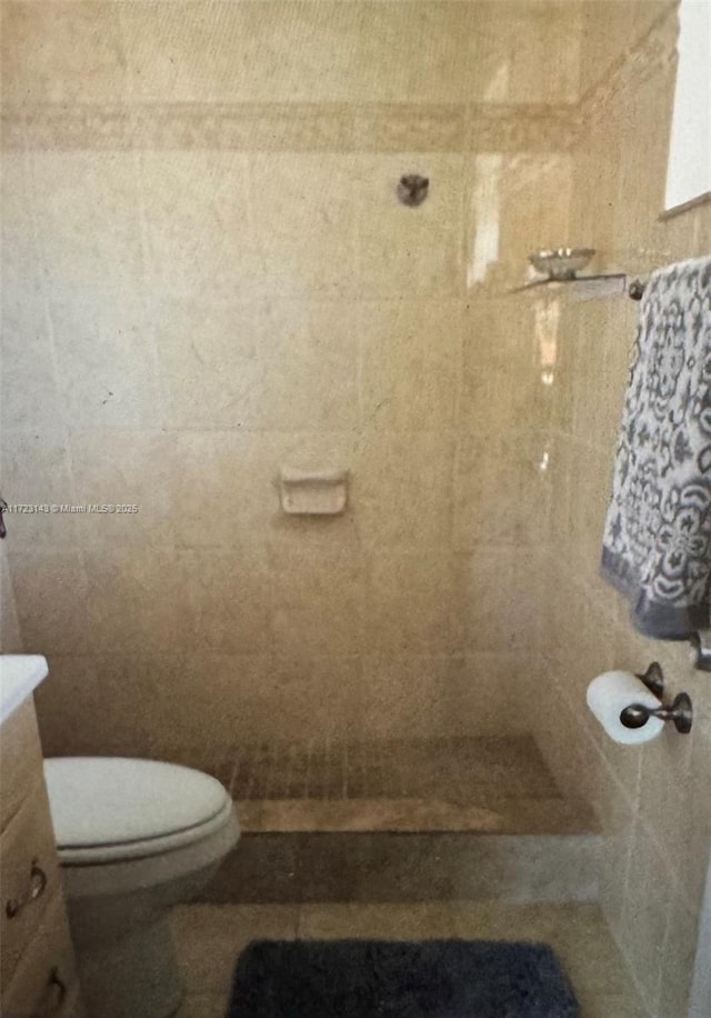 bathroom with tiled shower, vanity, and toilet