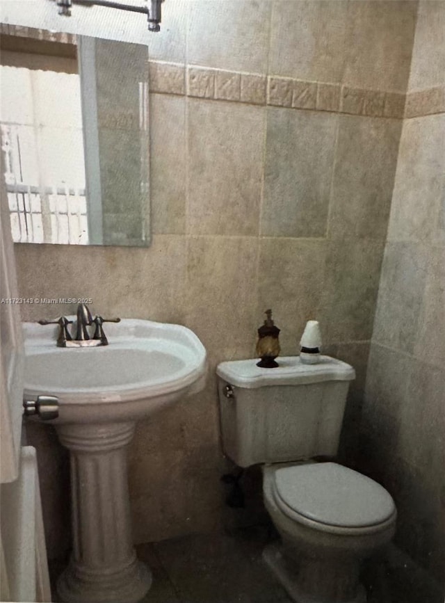 bathroom with tile walls and toilet