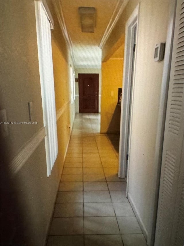 hall with tile patterned floors and crown molding