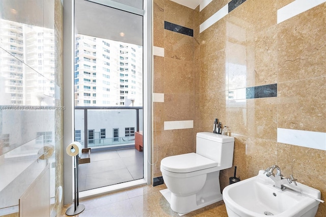 bathroom with a healthy amount of sunlight, sink, tile walls, and a bidet