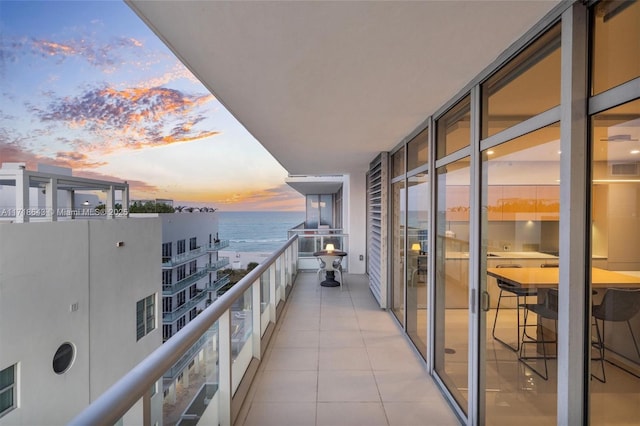 balcony at dusk featuring a water view