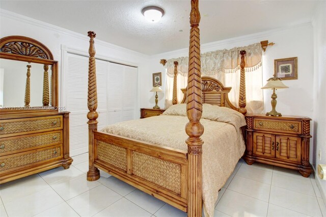 tiled bedroom with a closet, a textured ceiling, and ornamental molding