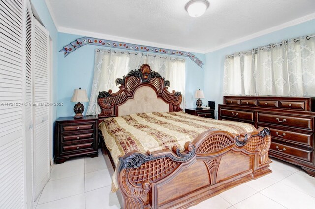 bedroom with crown molding, a closet, and light tile patterned floors